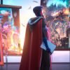 A character wearing a red cape and blue accents stands in front of a colorful display of images and objects.